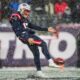 Bryce Baringer punts the ball in the middle of snow for the Patriots.