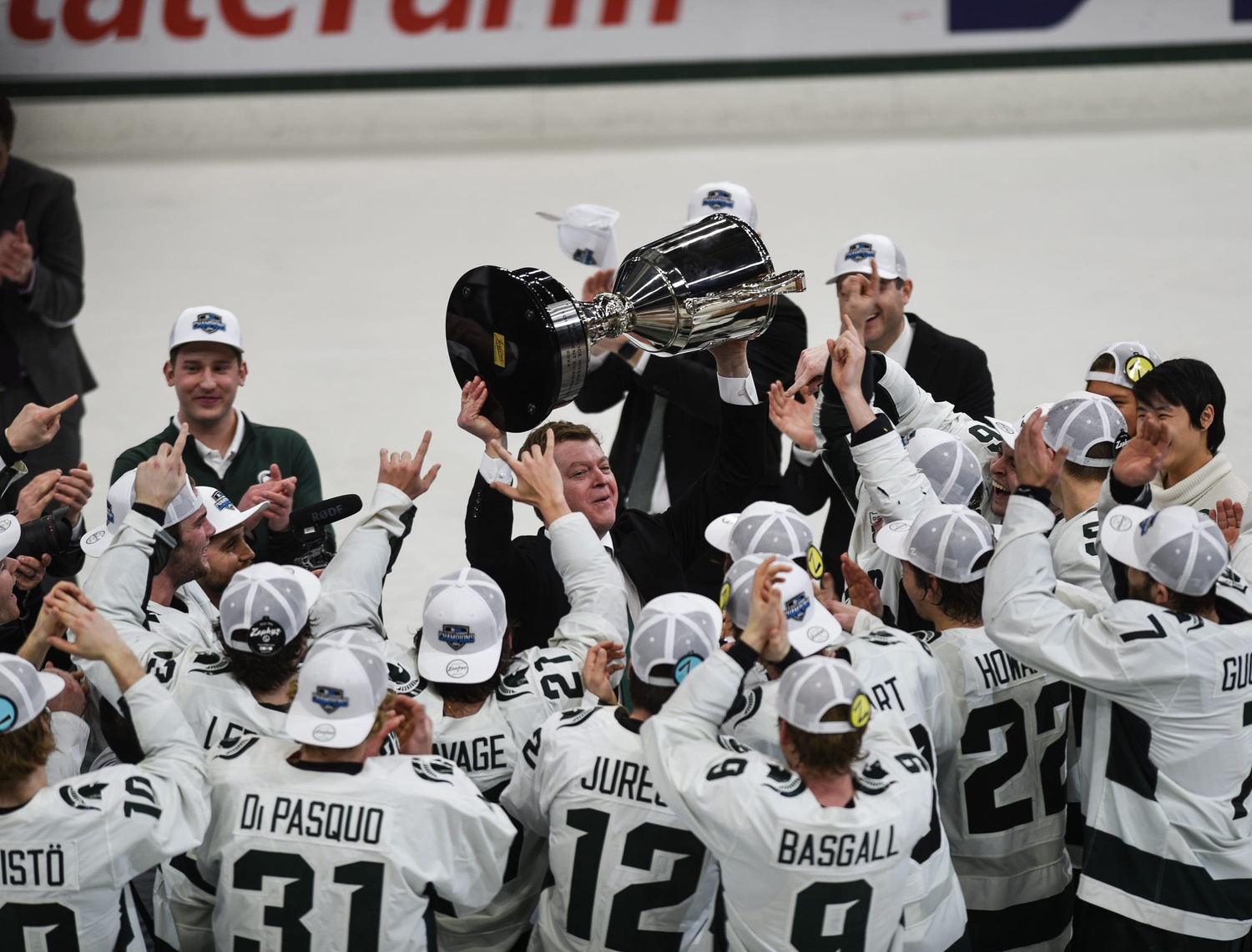 Michigan State hockey coach Adam Nightingale hoists the Big Ten Tournament championship trophy with his team.