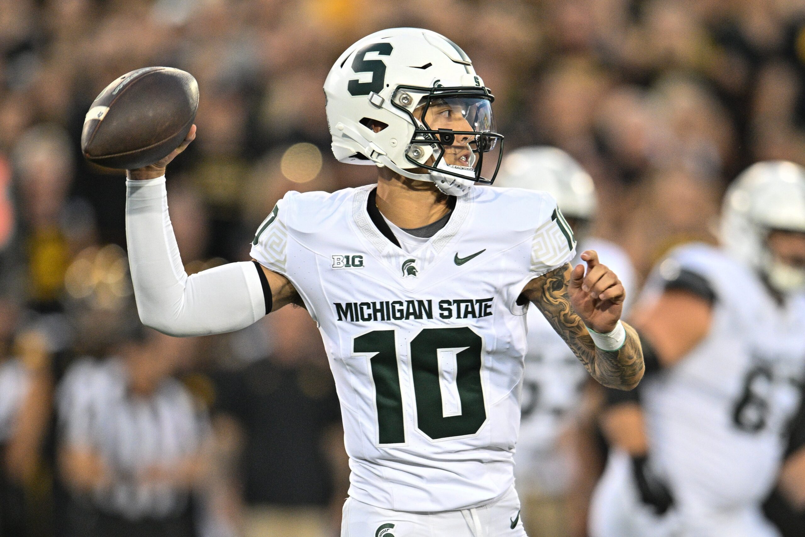 Former Michigan State football QB1 Noah Kim steps back to pass vs. Iowa.