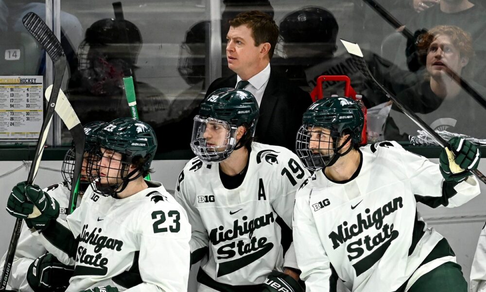 Michigan State hockey players react to a play on the bench.