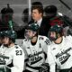 Michigan State hockey players react to a play on the bench.