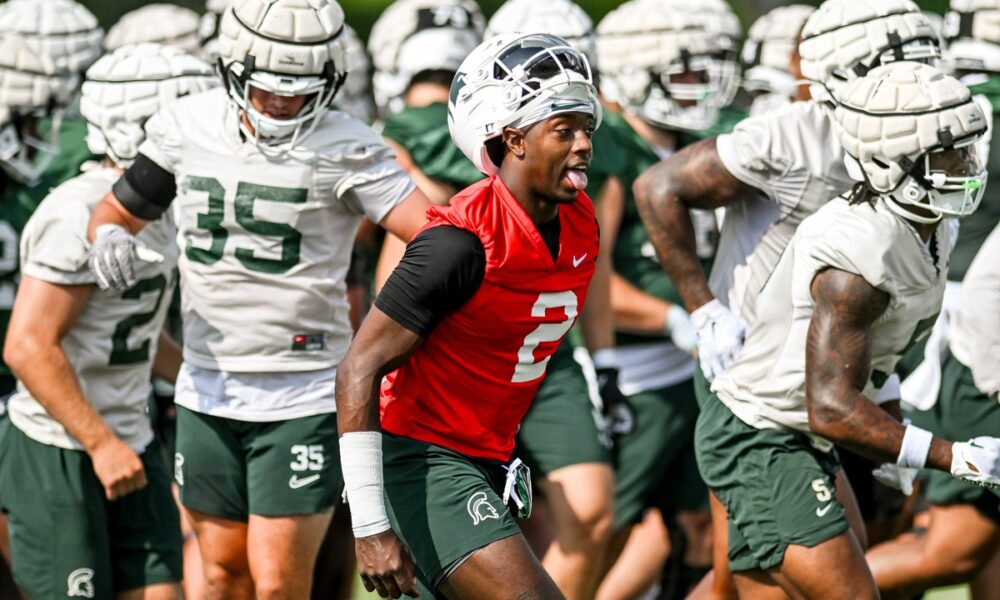 Aidan Chiles runs off the field with his Michigan State football teammates.