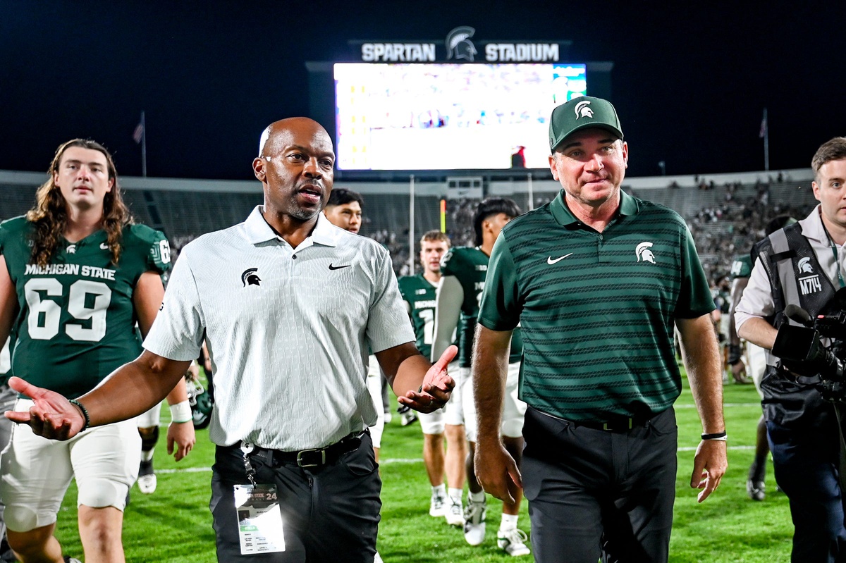 Michigan State football coach Jonathan Smith walks off the field with AD Alan Haller.