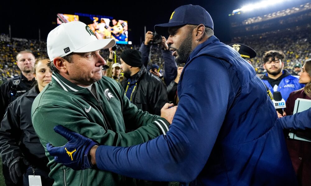 Michigan State football coach Jonathan Smith shakes Sherrone Moore's hand.